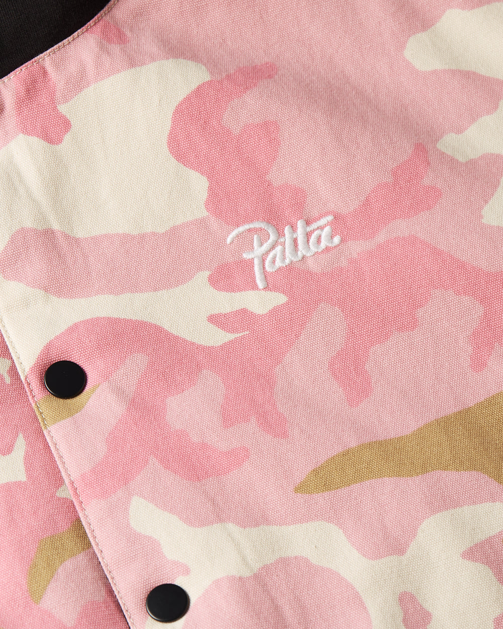 Detail shot of the embroidered patta script logo on the camo side of the reversible woodland camo bomber