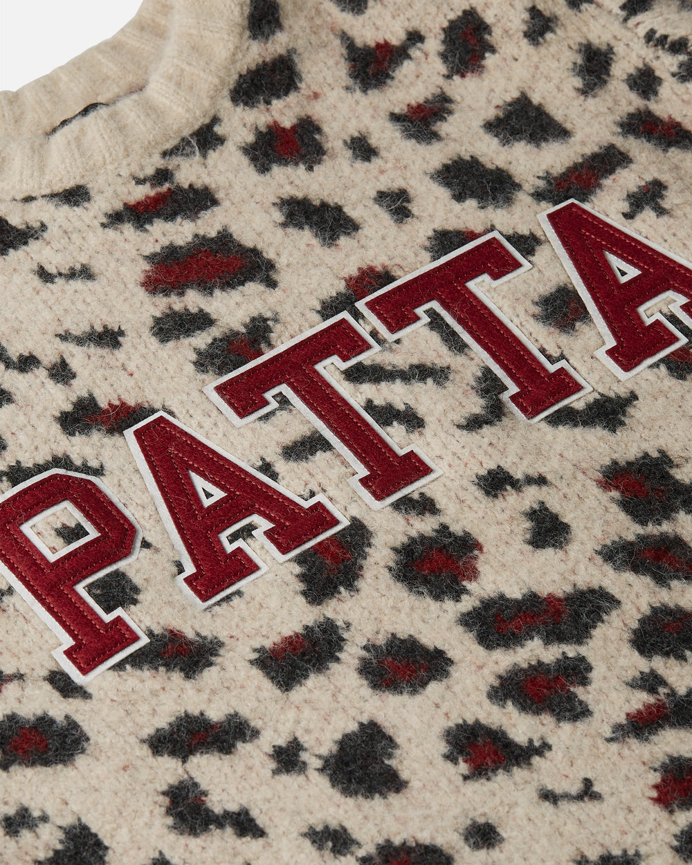 close up detail off the college style applique branding on the Leopard Brushed Knit